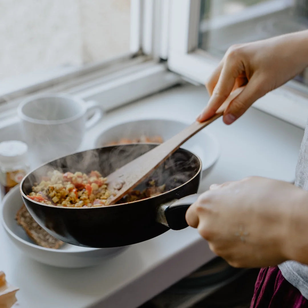 A person plating up hot healthy food from the saucepan 