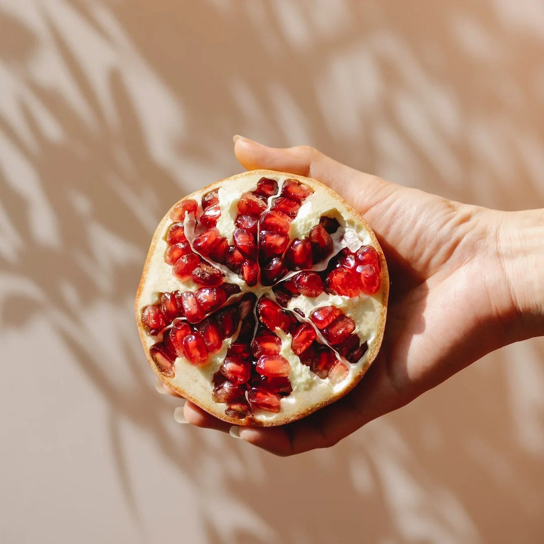 Holding halved pomegranate with shadow leaves in background