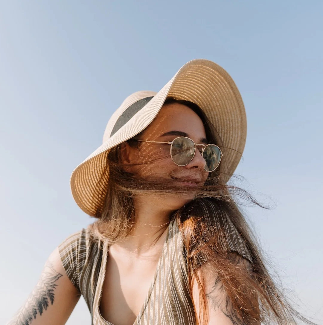 Woman wearing a large sunhat with wind blowing her hair across her face
